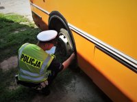 Policjant sprawdza stan techniczny autobusu szkolnego.